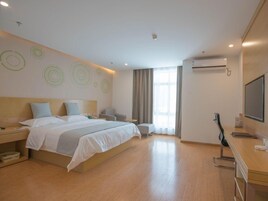 Una habitación de hotel moderna con una cama grande, mesitas de noche, un escritorio, una silla y un televisor.