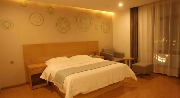 A hotel room with a large bed, bedside tables, a chair, and a view of the city through the window.
