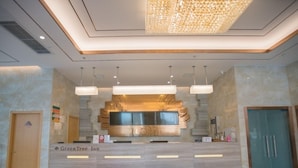 A hotel reception area with a marble counter, a red carpet, and a modern chandelier. - Greentree Inn Hefei Huaxia International Chabocheng Branch (Hefei)