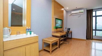 Habitación de hotel con tocador de madera, televisor, escritorio y ventana con cortinas.