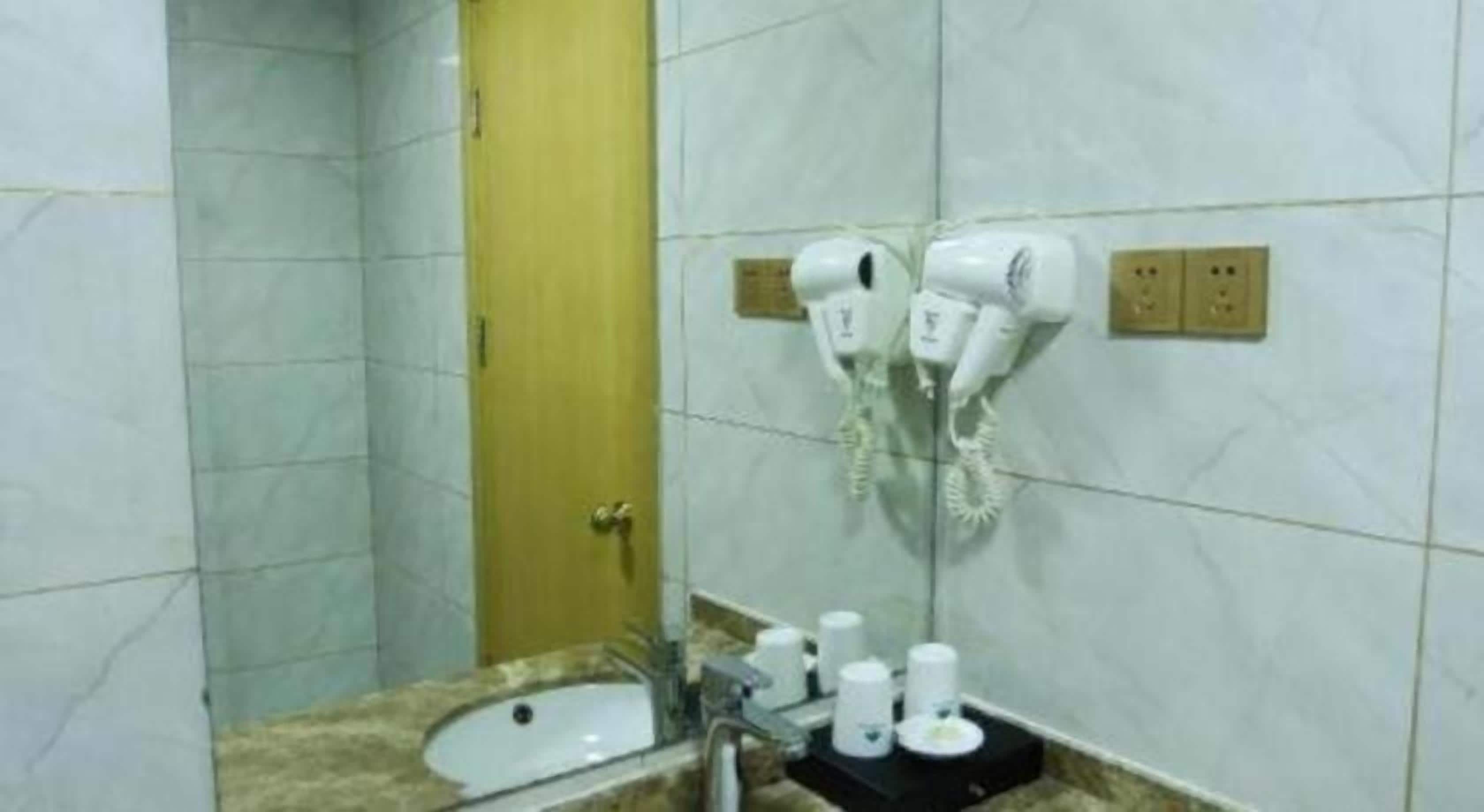 A bathroom with a sink, a mirror, and two hair dryers mounted on the wall.