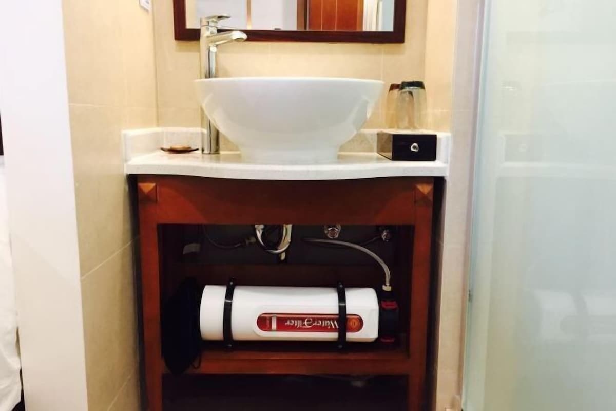 A bathroom with a white sink, a mirror above it, and a towel warmer below.