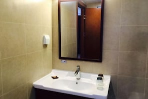 A bathroom with a white sink, a mirror, and a towel dispenser. - S One Hotel (Shanghai)