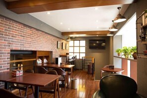 A restaurant with brick walls, wooden tables, and chairs. There are shelves with books and a window in the background. - S One Hotel (Shanghai)