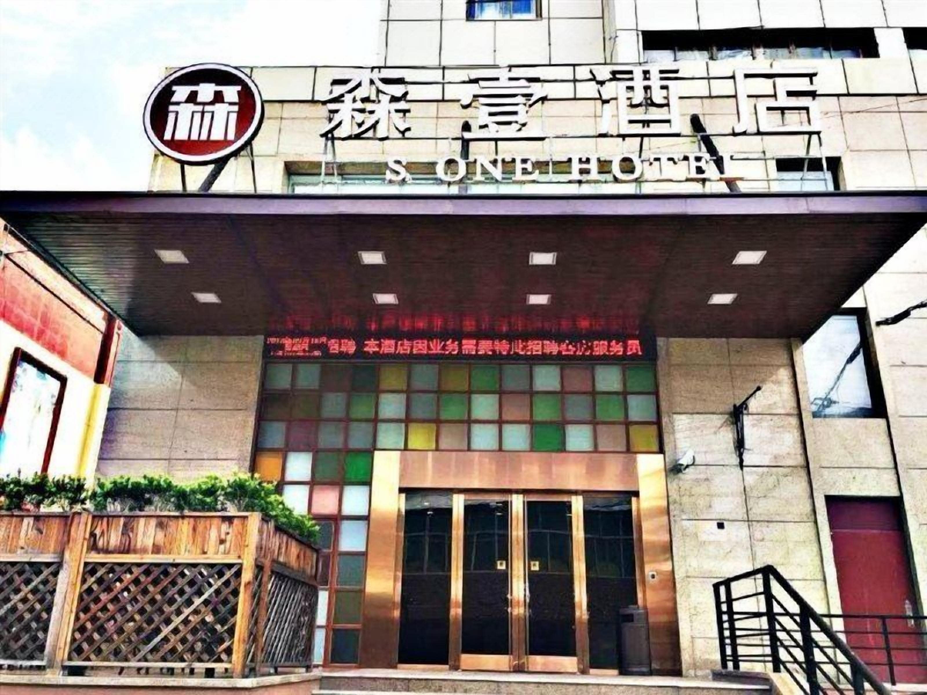 A hotel entrance with a modern facade, a prominent logo, and a sign indicating the hotel's name.