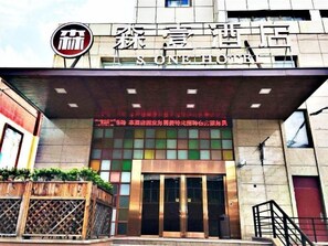 A hotel entrance with a modern facade, a prominent logo, and a sign indicating the hotel's name. - S One Hotel (Shanghai)