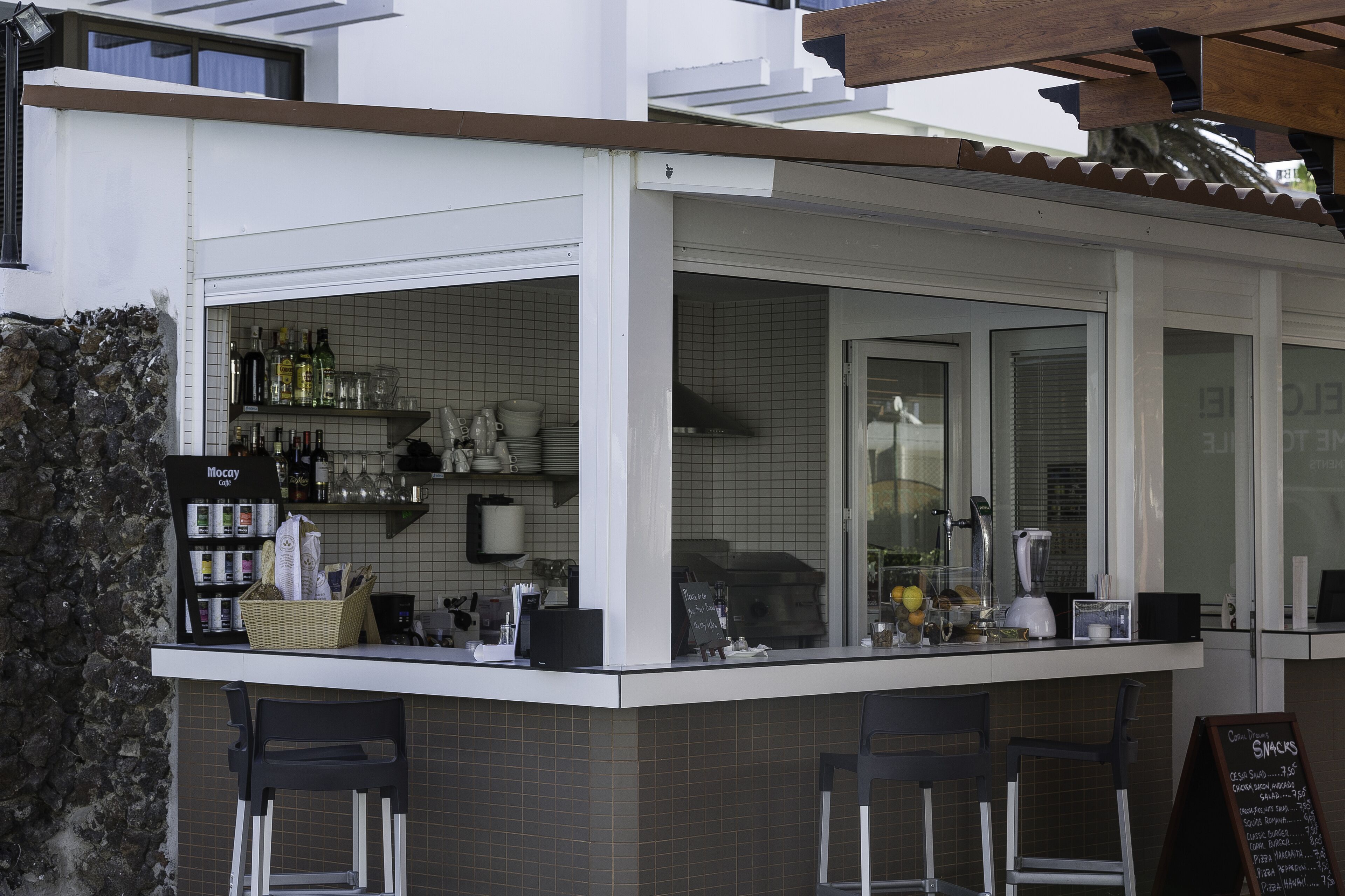 Een klein buitengebied met een bar, krukken en een menubord.