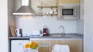 A modern kitchen with a microwave, toaster, kettle, and a glass bowl with fruit on the counter. - Coral Dreams (Adeje)