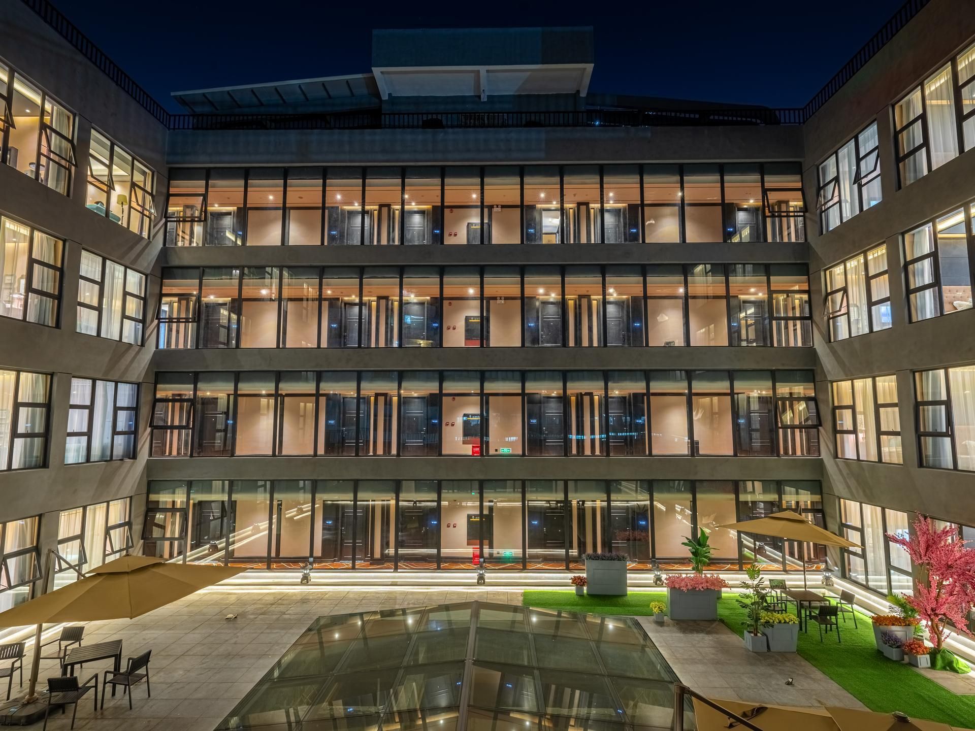 A multi-story building with a central courtyard, glass railings, and outdoor seating.