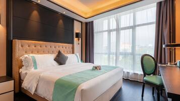 A hotel room with a large bed, a desk, and a chair.