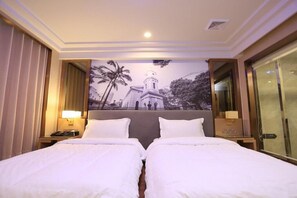 Habitación de hotel con dos camas, un mural grande de un edificio y una mesita de noche con una lámpara.