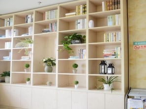 A library with wooden bookshelves filled with books and potted plants. - Greentree Inn Shanghai Car Piers Studio Beisong Ro (Shanghai)