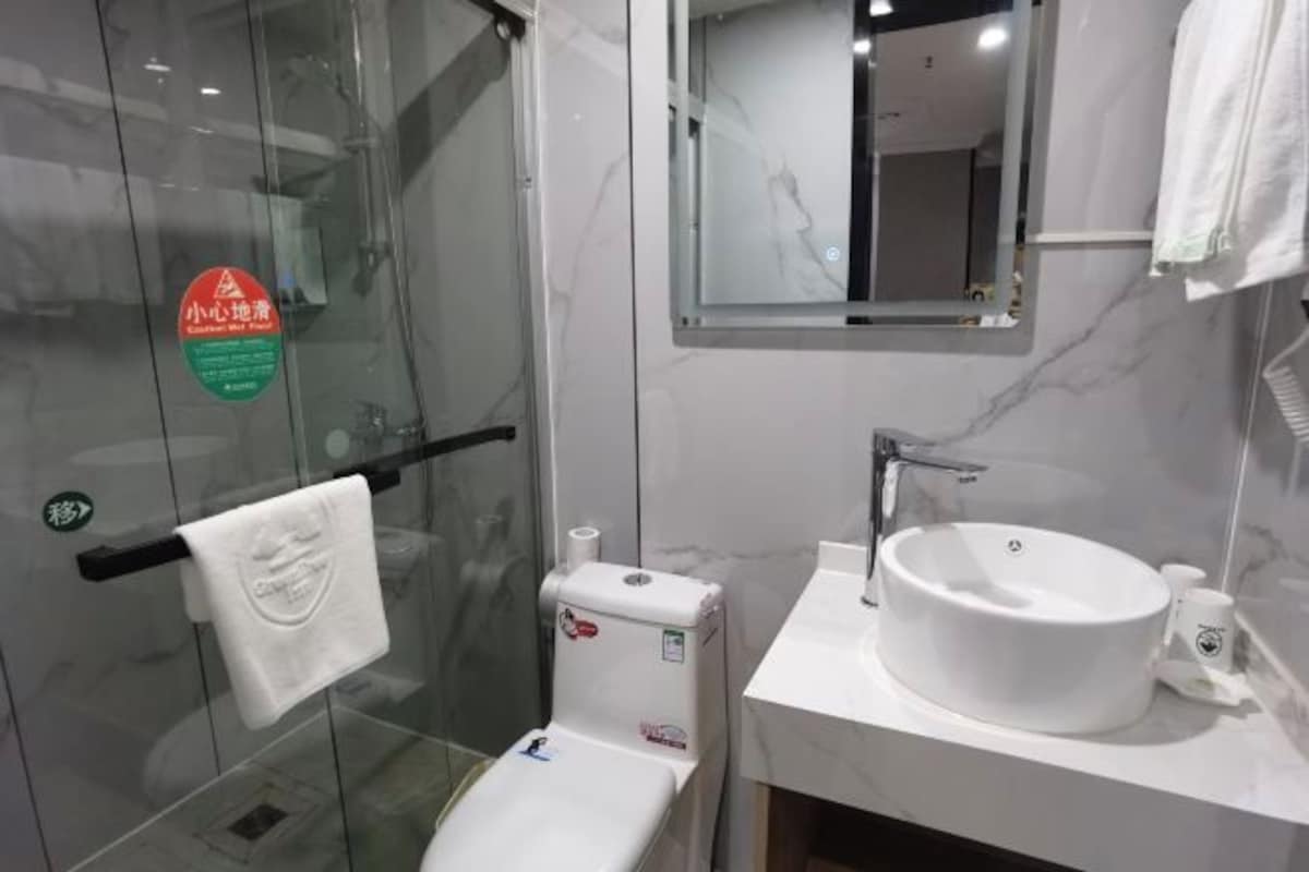 Une salle de bain moderne avec une douche à parois de verre, un lavabo blanc et un miroir au-dessus du lavabo.