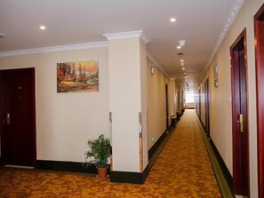 Ein Hotel-Flur mit Teppichboden, Holztüren und einem Gemälde an der Wand.