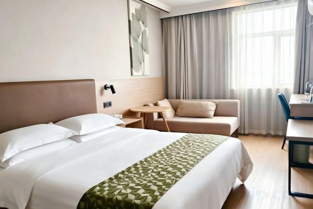 A hotel room with a bed, a sofa, a small table, and a desk.