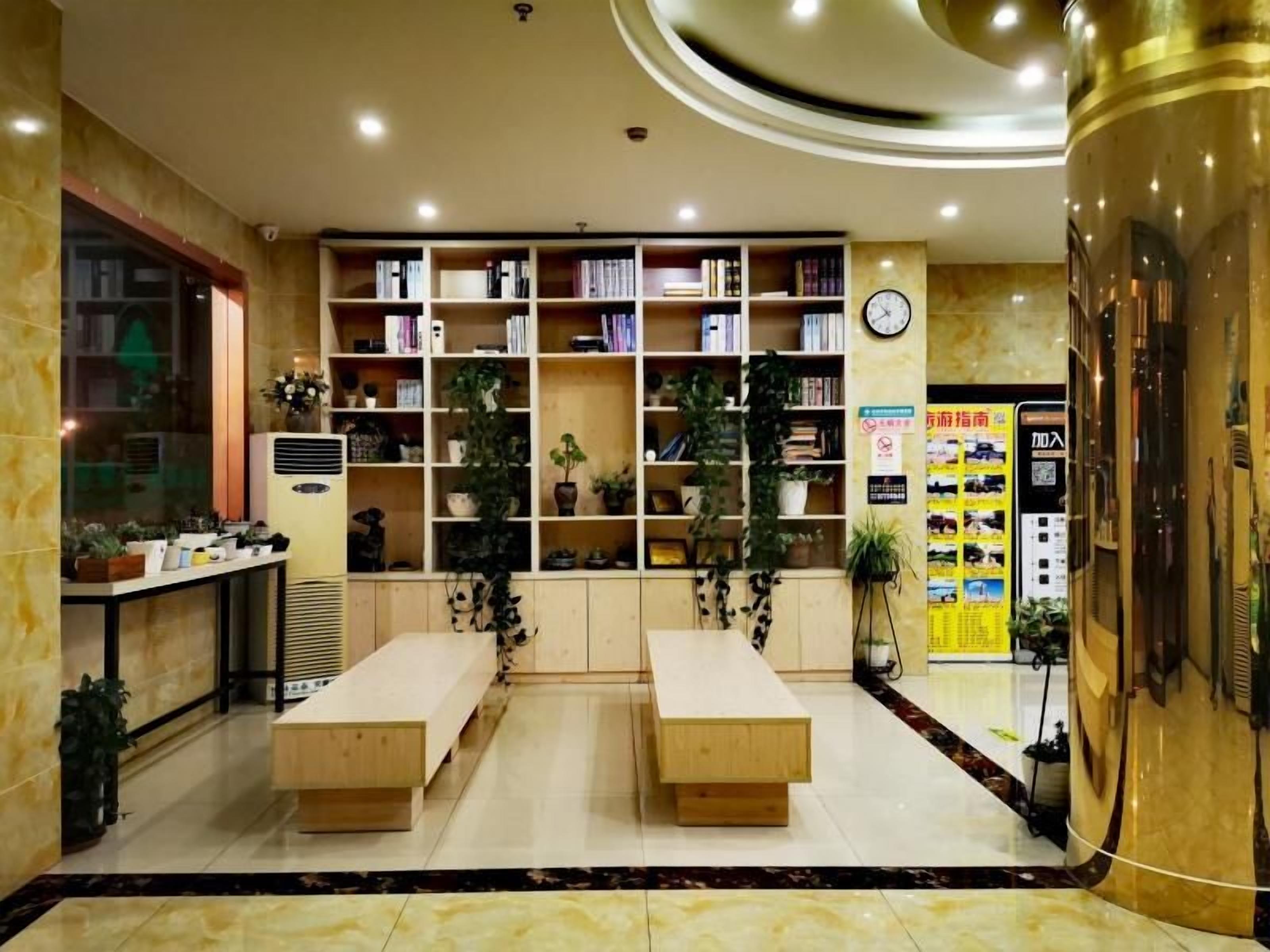 A hotel lobby with a reception desk, a large bookshelf, and a seating area.