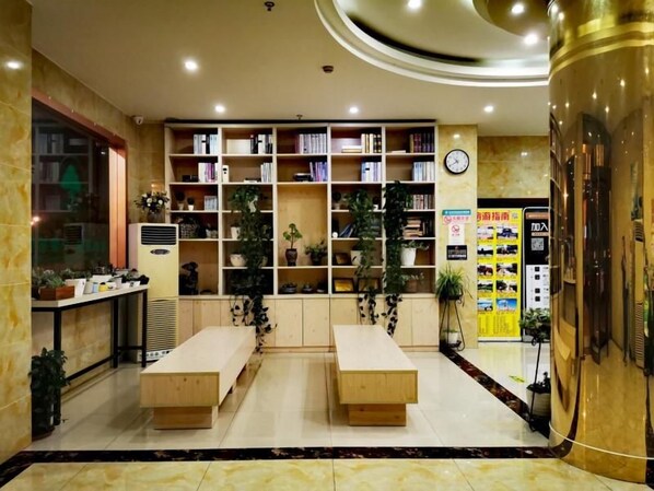 A hotel lobby with a reception desk, a large bookshelf, and a seating area.