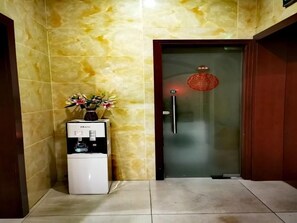 Un distributeur d’eau et une porte surmontée d’une lanterne rouge.