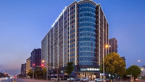 A high-rise hotel with a curved facade, multiple floors, and a prominent signage at the ground level.