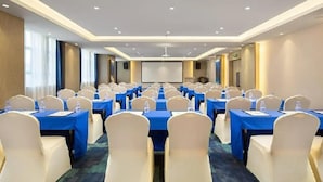 A conference room with rows of tables and chairs, equipped with water bottles and name tags.