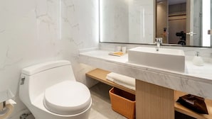A modern bathroom with a white toilet, a large mirror, and a white sink.