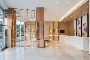 A modern interior with a reception desk, a seating area, and a display wall.