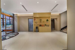 A spacious lobby with a reception desk, a staircase, and a door leading to another area. - Urban Garden Hotel (Qingdao)