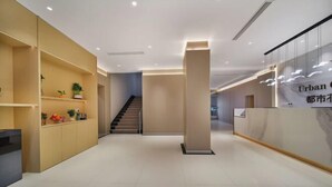 A modern interior with a reception desk, a staircase, and a minimalist design. - Urban Garden Hotel (Qingdao)