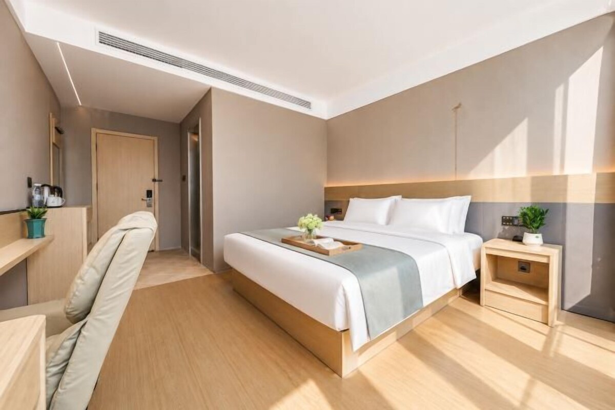 Una habitación de hotel moderna con una cama grande, una mesita de noche y un escritorio.