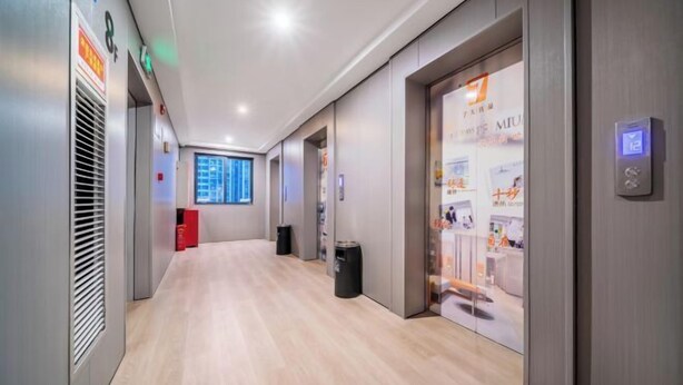 A modern hotel corridor with a wooden floor, a red seating area, and a glass wall displaying a poster. - 7 Days Premium (Chongqing Liangjiang New District, Yufu Industrial Park, Yuzui) (Chongqing)