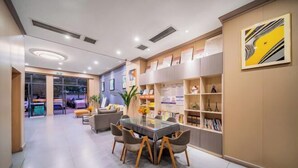 A modern hotel lobby with a glass-top dining table, comfortable seating, and a bookshelf with informational materials. - 7 Days Premium (Chongqing Liangjiang New District, Yufu Industrial Park, Yuzui) (Chongqing)