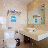Un baño con un lavamanos blanco, un inodoro, un cubo de basura y un espejo.