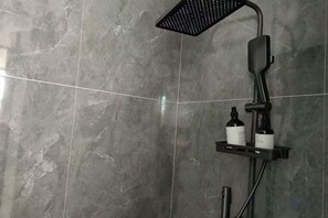 Un espace douche au design moderne, comprenant une douchette à pluie et un pommeau de douche amovible.