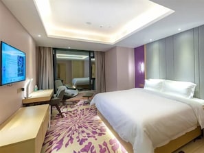 Une chambre d’hôtel avec un lit, un bureau, une chaise, une télévision et une grande fenêtre.