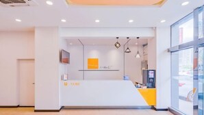 A reception area with a white counter, a glass door, and a vending machine. - 7Days Inn Hotel (Huizhou Zhongkai Chenjiang Avenue) (Huizhou)