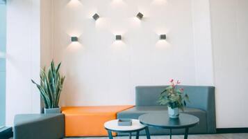 Un espace d’attente moderne, aménagé avec un canapé, une petite table et une plante en pot.