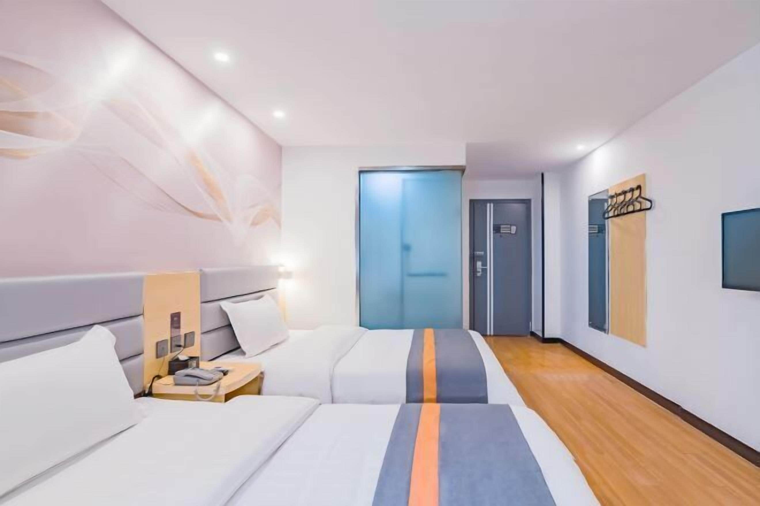 A modern hotel room with a large bed, bedside tables, a desk, and a wardrobe.