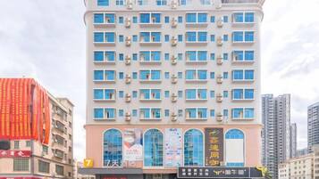 Un hotel de varios pisos con fachada moderna, múltiples balcones y una entrada destacada con señalización.