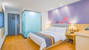 A hotel room with a bed, bedside table, and a desk with a chair. There is a wardrobe and a door with a handle. - 7Days Inn Hotel (Huizhou Zhongkai Chenjiang Avenue) (Huizhou)