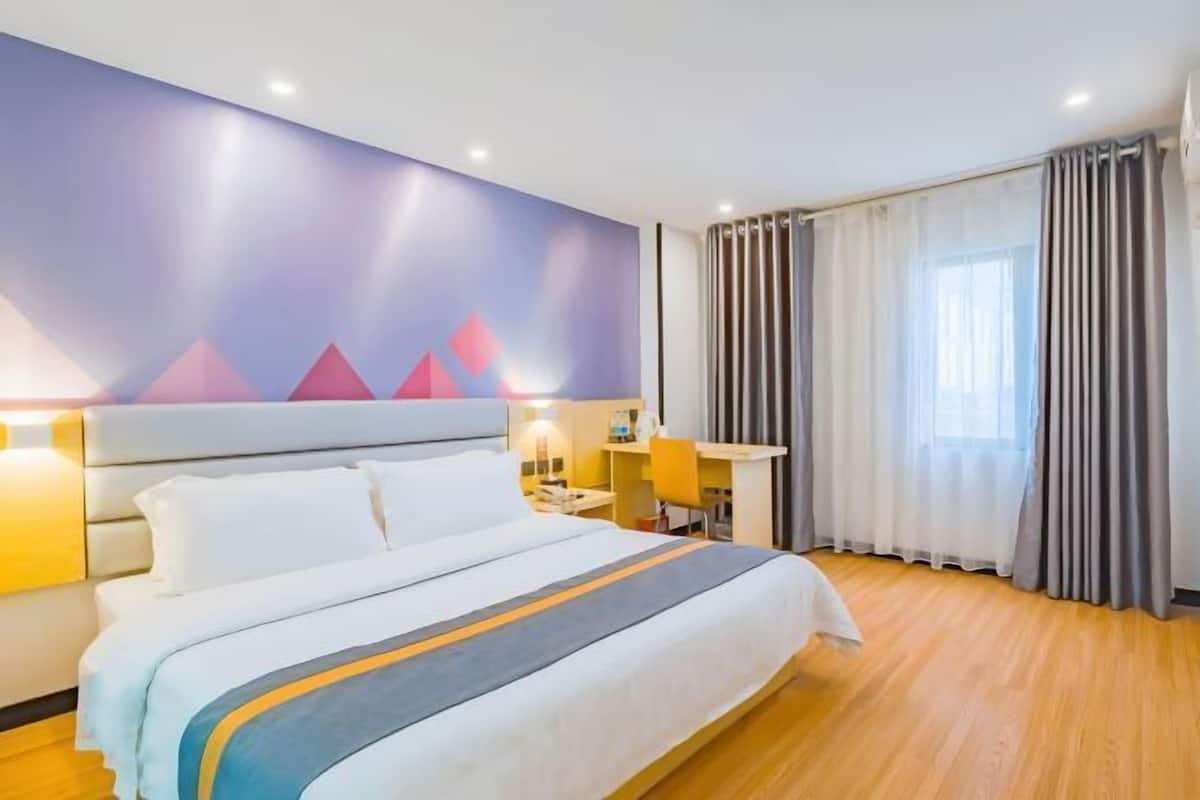 A hotel room with a bed, a desk, a chair, and a window with curtains.