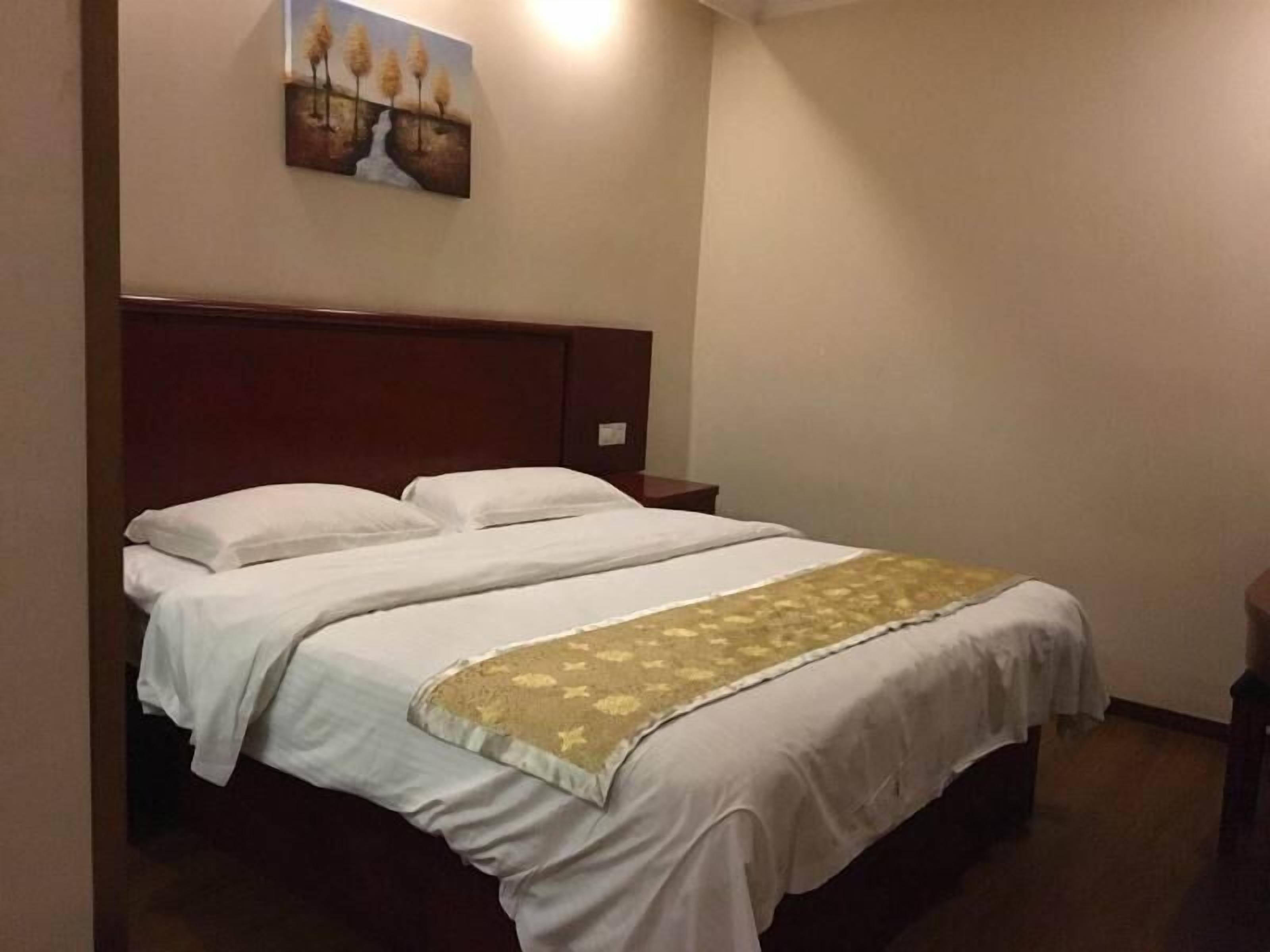 Ein Hotelzimmer mit einem großen Bett, einem Kopfteil, einem Nachttisch und einem Bild an der Wand.