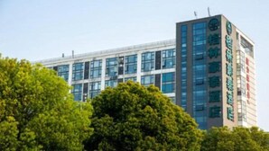 Un edificio moderno con varios pisos, ventanas amplias y un cartel llamativo en la fachada.