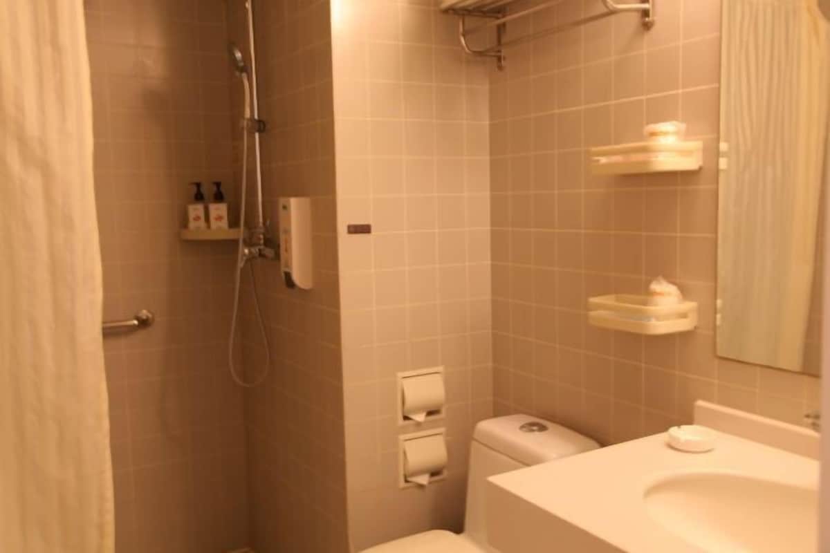 Casa de banho com chuveiro, sanita, lavatório e porta-toalhas.