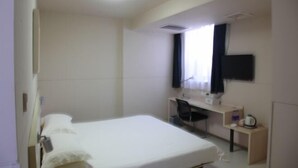 A hotel room with a single bed, a desk, a chair, a TV mounted on the wall, and a window with curtains. - Jinjiang Inn (Anyang Railway Station) (Anyang)