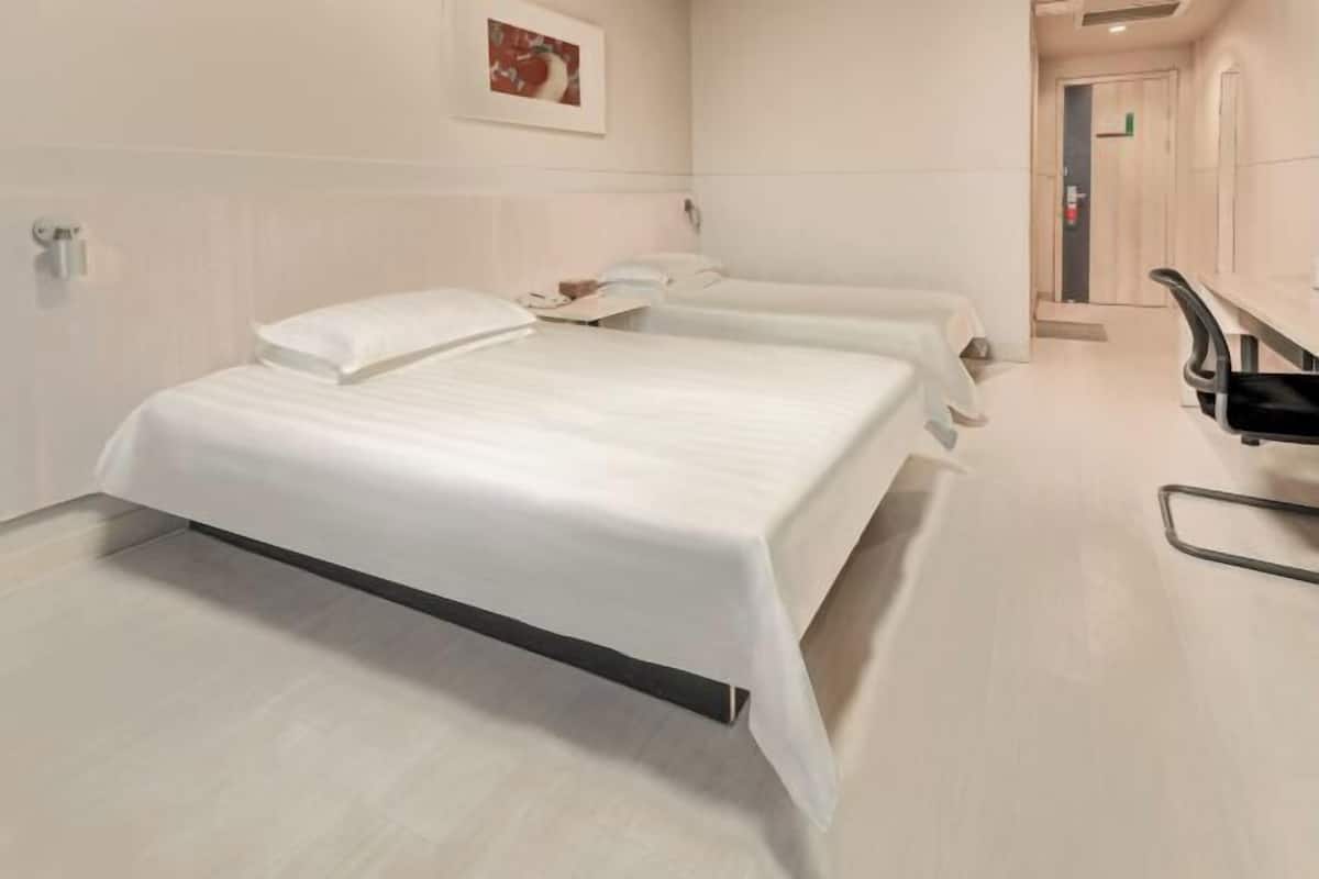 A hotel room with two beds, a desk, and a chair.