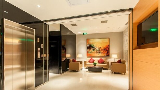 A modern lobby with a glass elevator, a large abstract painting, and a reception desk. - Jinjiang Inn (Anyang Railway Station) (Anyang)