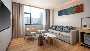 A modern hotel room with a large window, a sofa set, a coffee table, and a minibar. - Holiday Inn Express Ziyang City Center by IHG (Ziyang)