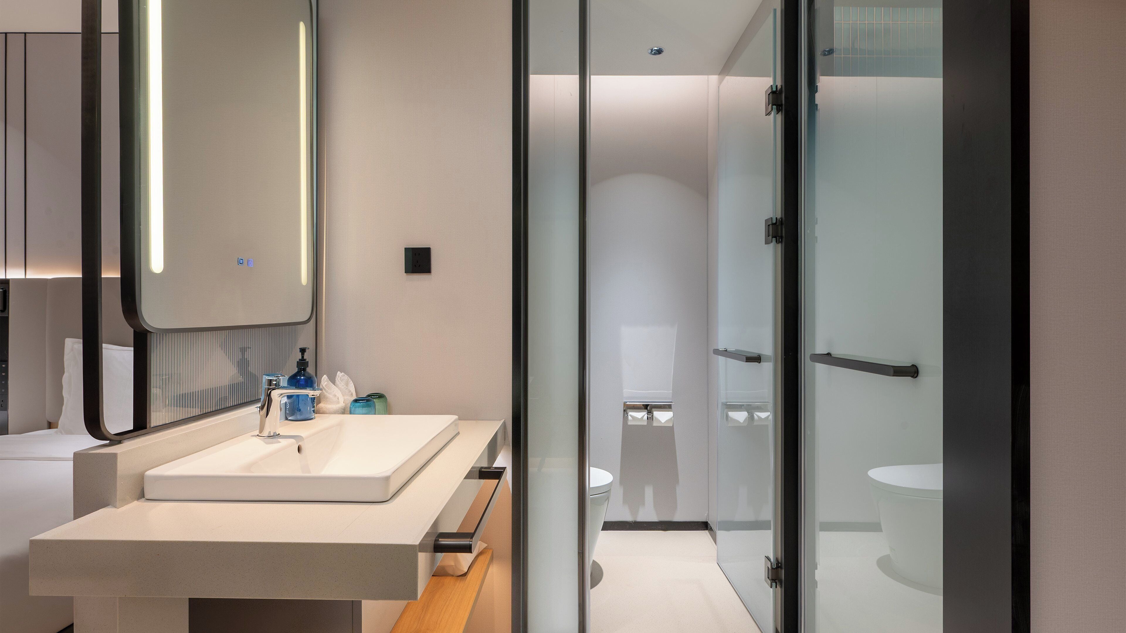 A modern bathroom with a large mirror, a sink, and a toilet.