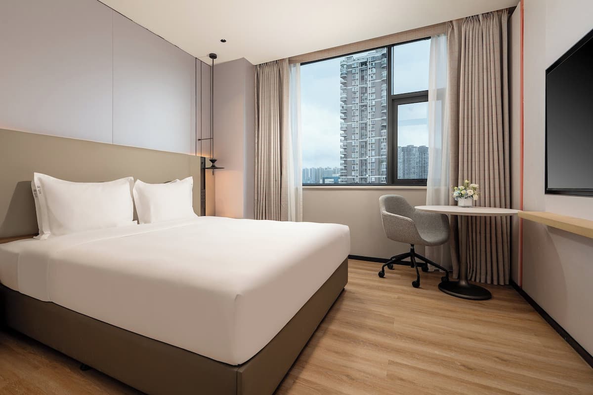 Une chambre d’hôtel avec un grand lit, un bureau, une chaise et un téléviseur.