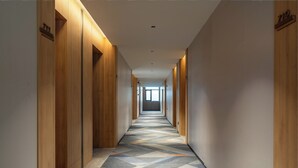 A long, narrow hallway with wooden paneling on the walls and a patterned carpet. - Holiday Inn Express Ziyang City Center by IHG (Ziyang)